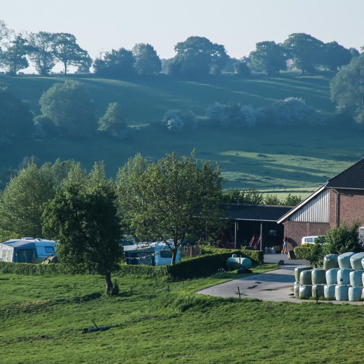 boerderij met aangrenzende campingplaats tussen de glooiende heuvels.