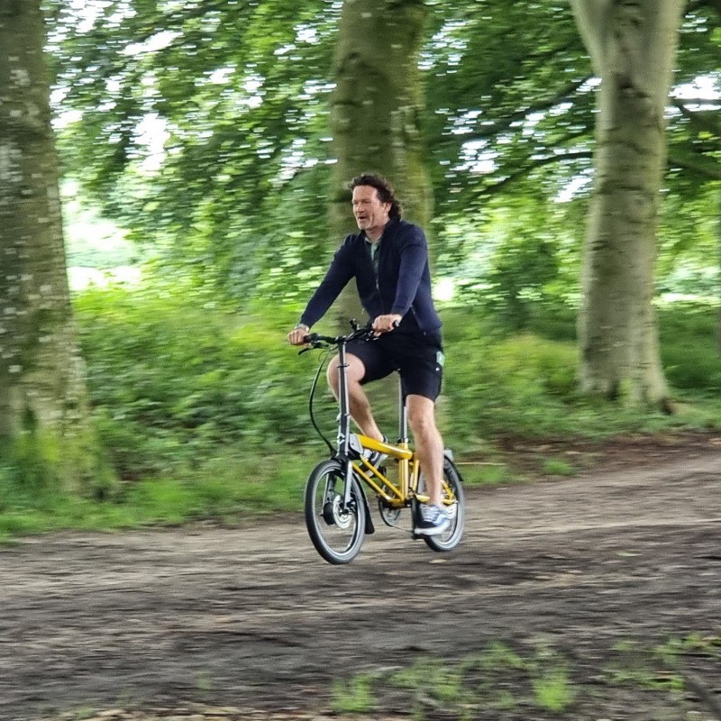 Sander fiets op een elektrische vouwfiets door het bos. 