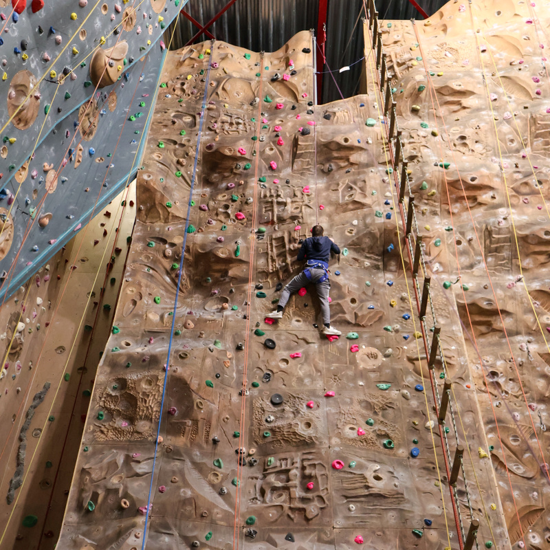 Persoon hangt aan de klimwand in gulpen. 