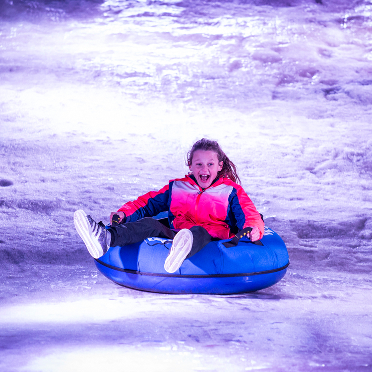 Wintertijd Heerlen, meisje op band glijdt naar beneden van sneeuwbaan