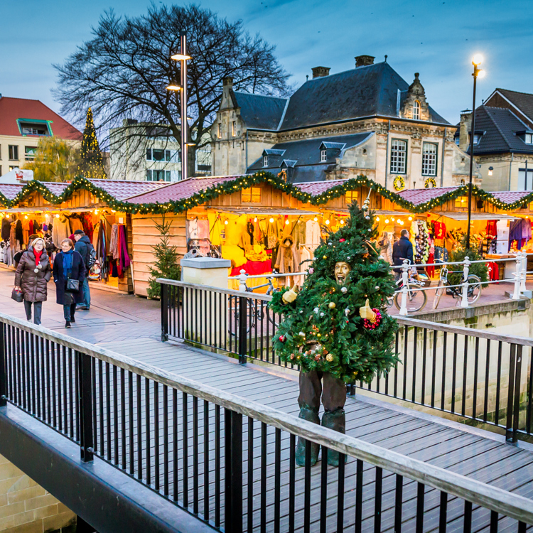 Als kerstboom verkleed persoon staat op het bruggetje voor Santa's Village