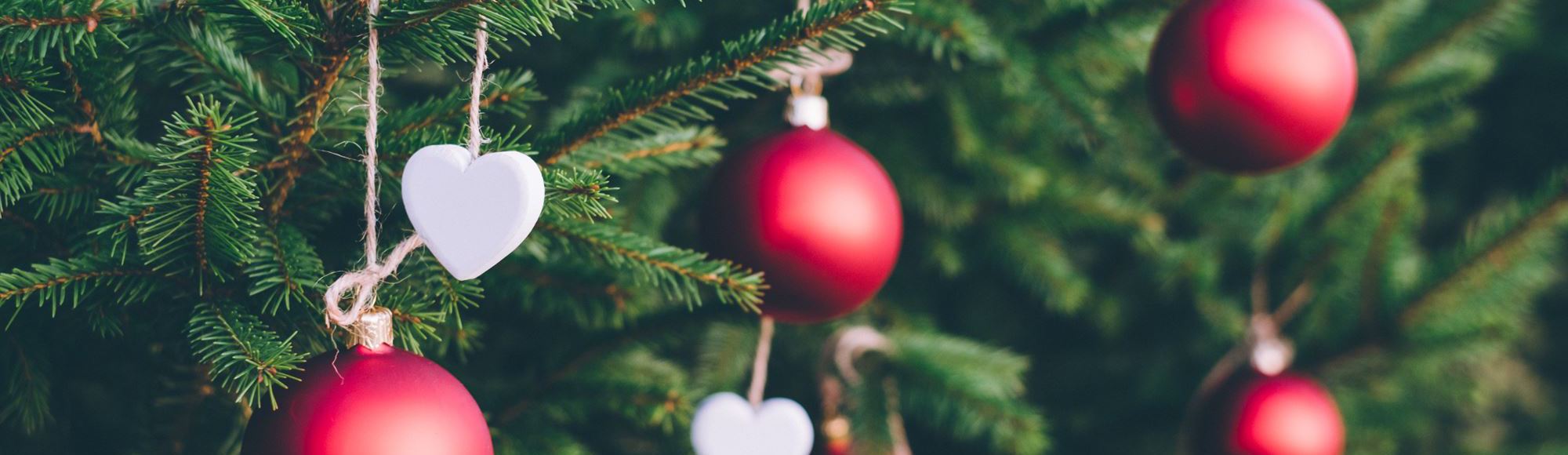 Close up van rode kerstballen en witte hartjes in dennenboom
