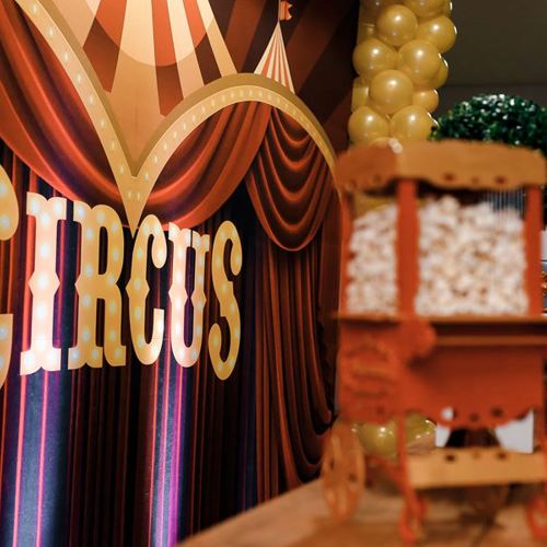 Rood theaterdoek met het woord 'circus' en daarvoor een mini popcornmachine