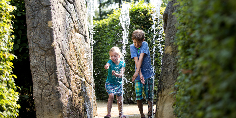 Kinderen rennen door fontein bij het Drielandenpunt doolhof