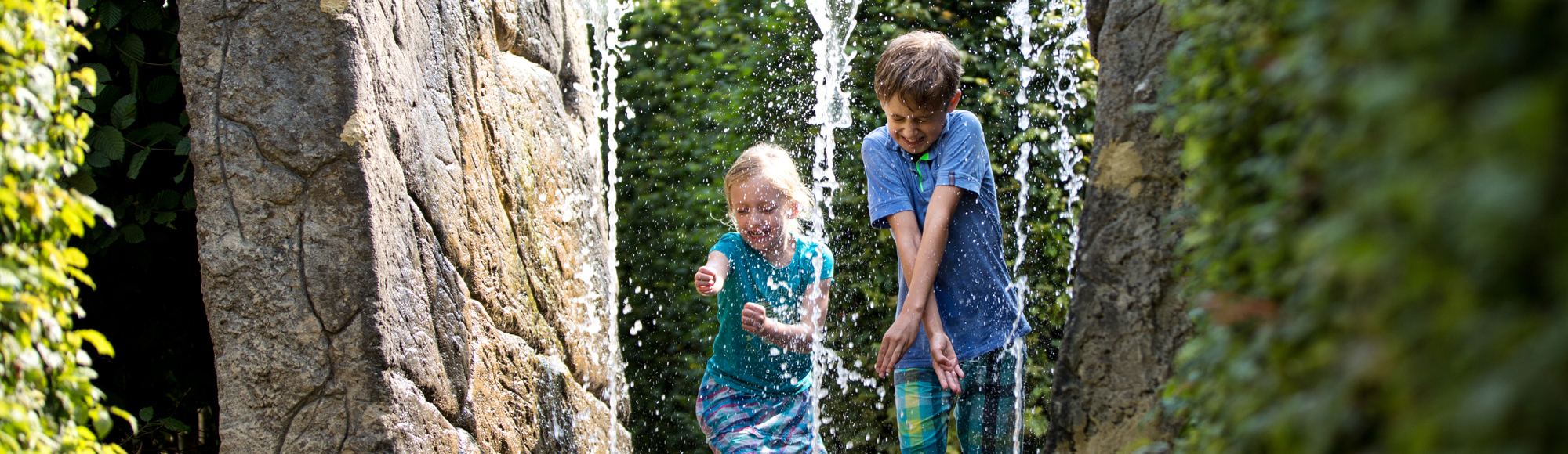 Kinderen rennen door fontein bij het Drielandenpunt doolhof