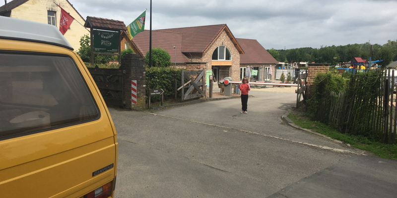 Ingang van de camping met het gele camperbusje ervoor. 