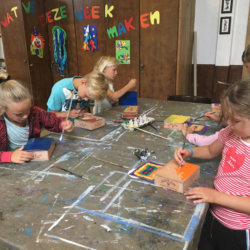 kinderen druk aan het schilderen als activiteit op de camping. 
