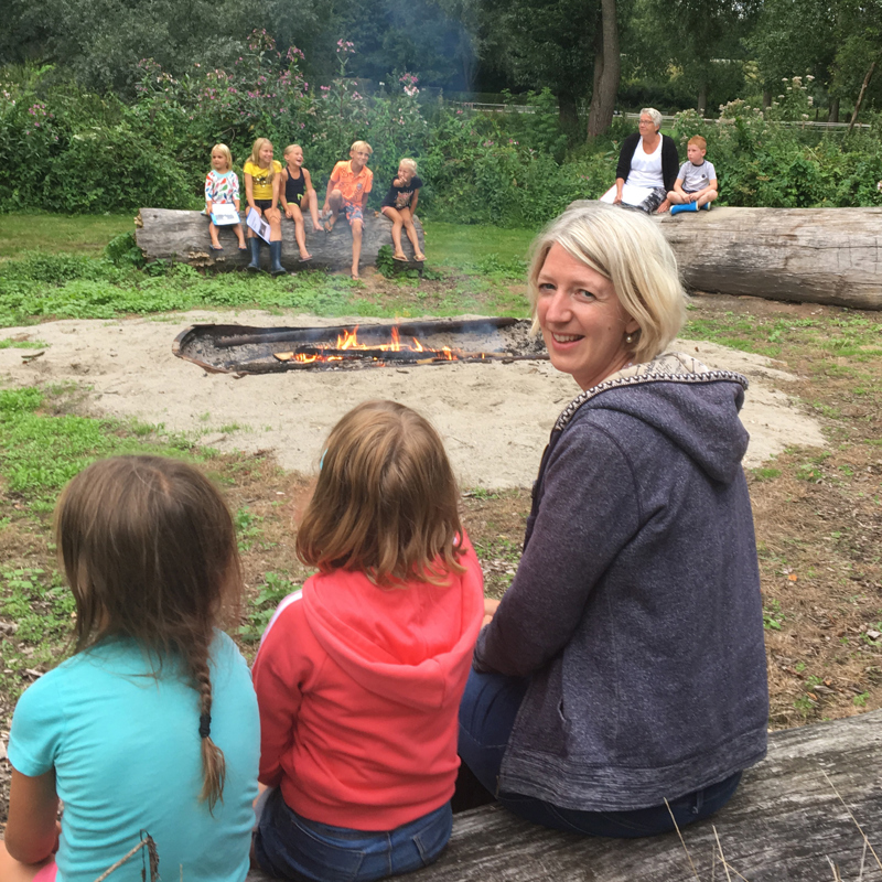 Moeder en kinderen genieten van een kampvuur op de camping. 