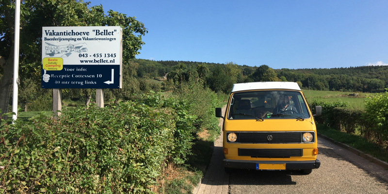 Geel camperbusje bij de ingang van de camping. 