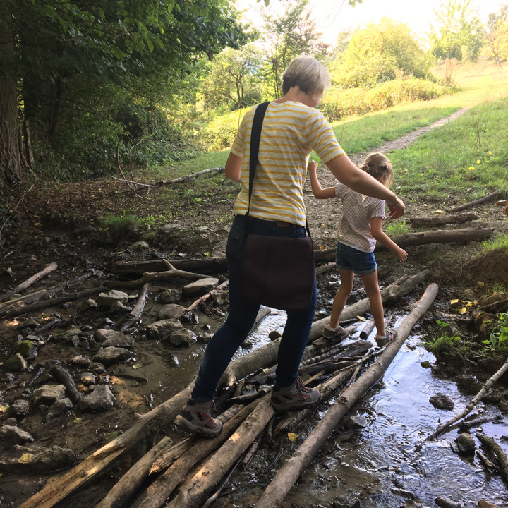 Moeder en dochter wandelen voorzichtig over de takken over het water. 