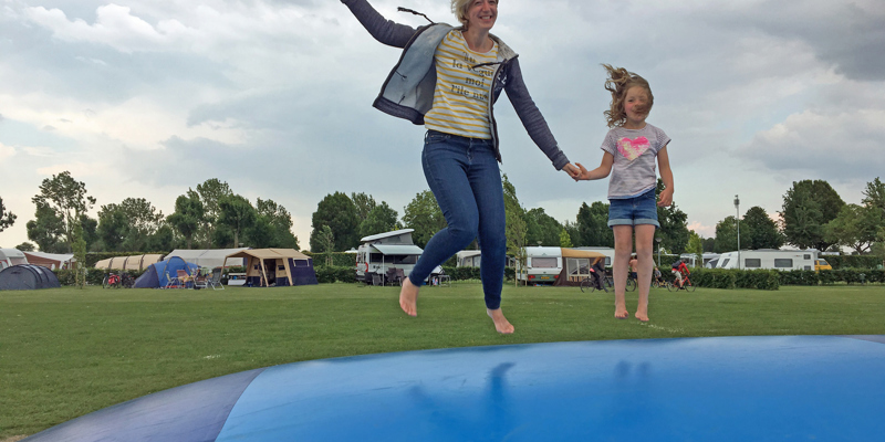 Moeder en dochter springen op een springkussen op de camping. 