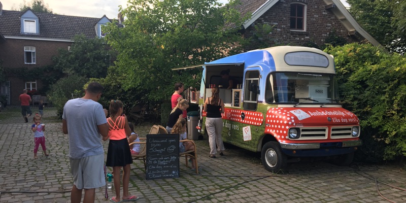 Campinggasten staan in de rij voor een rollende ijskraam. 