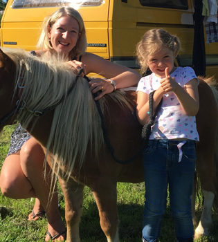 kindje en mama poseren met pony op de camping. 