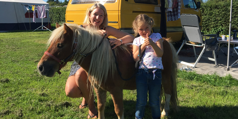 kindje en mama poseren met pony op de camping. 