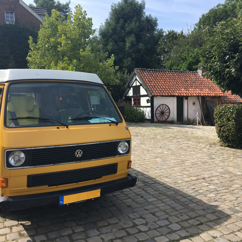 Geel camperbusje op een binnenplaats van de camping. 