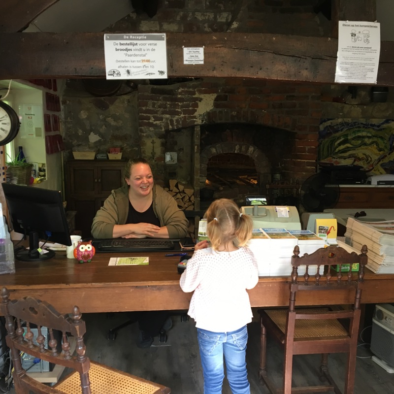 Meisje staat aan de receptie van een historische camping. 