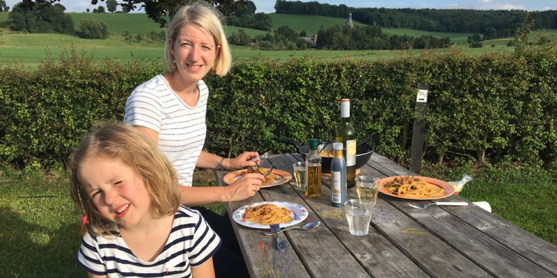 Moeder en dochter aan een picknicktafel aan de pasta op de camping. 