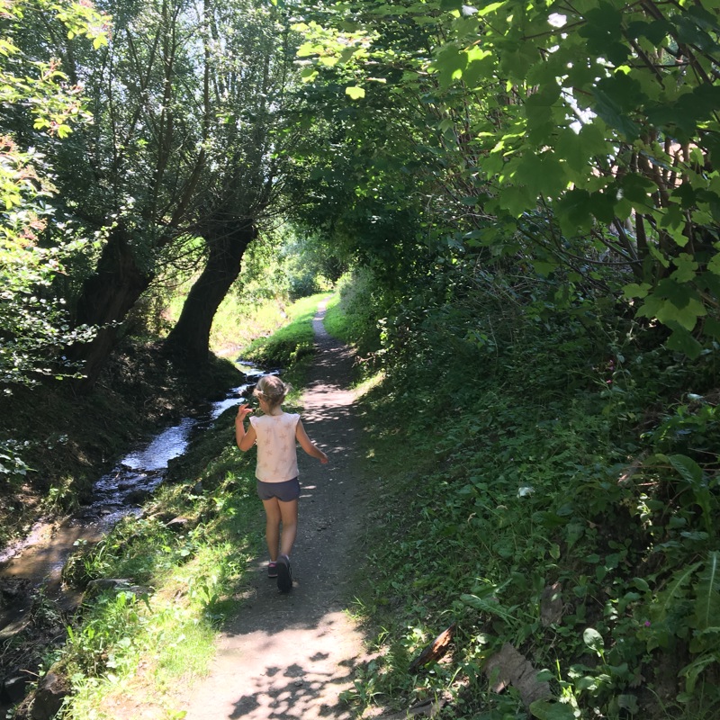 Meisje wandelt op een kronkelend wandelpad naast het water. 