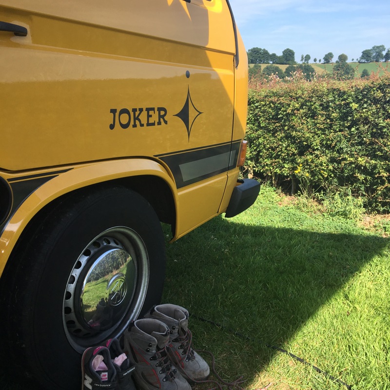 close-up van een geel busje met de wandelschoenen ervoor. 