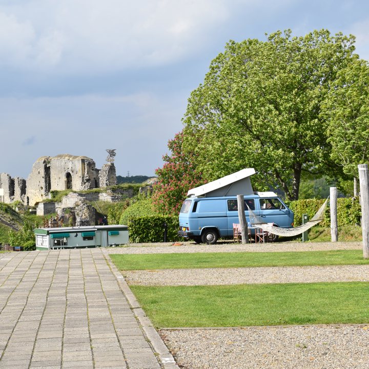 Camperplaats met een lichtblauw camperbusje. 