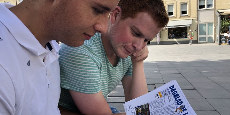 De jongemannen kijken naar krantenartikelen op een plein in Valkenburg