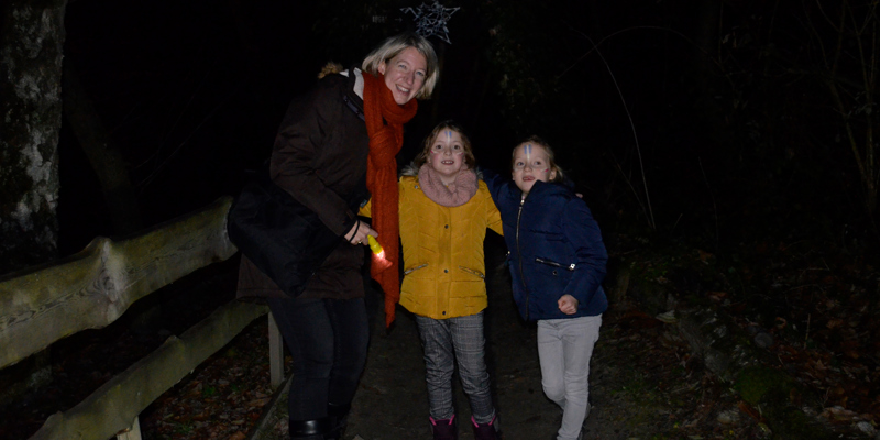 Vrouw en 2 meisjes met zaklamp in het bos