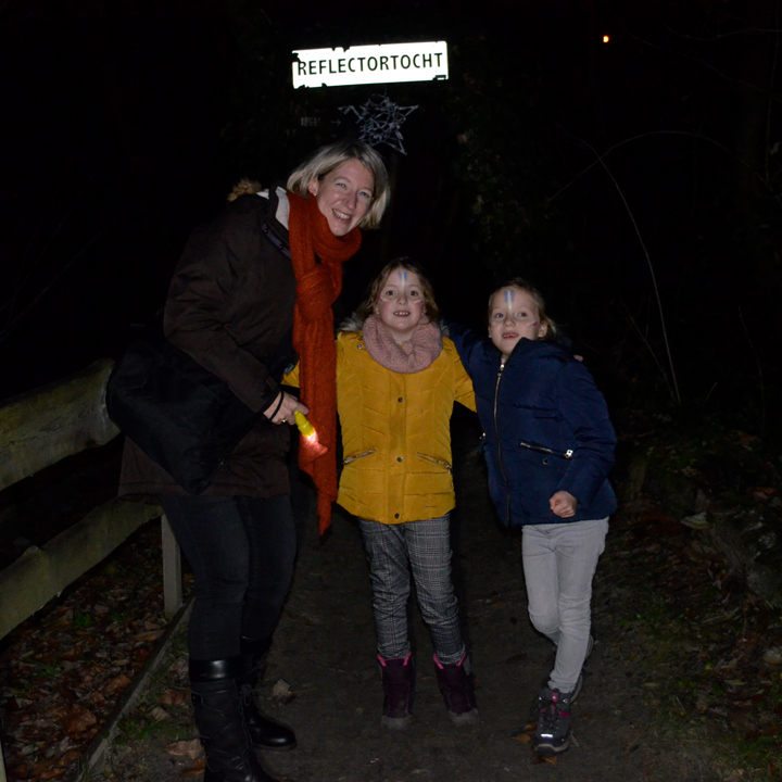 Vrouw en 2 meisjes met zaklamp in het bos