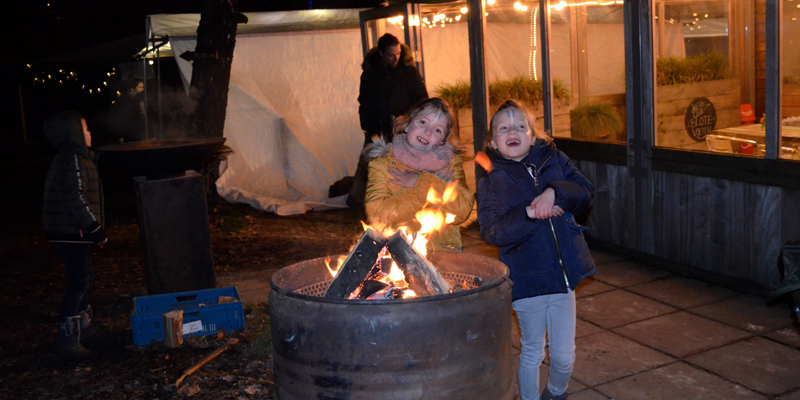 Kinderen warmen zich op aan vuur in olievat