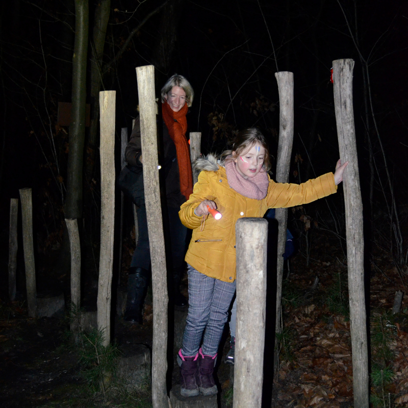 Meisje en vrouw balanceren op boomstammen in het donker