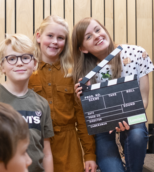 Jonge vrouw en 3 kinderen poseren met filmklapper