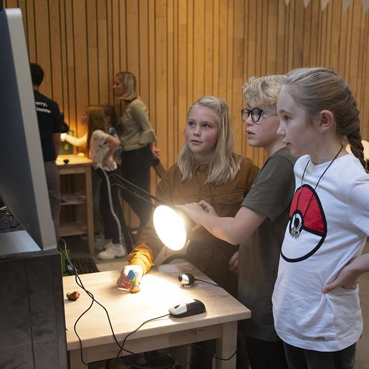 Kinderen schijnen met lamp op poppetje terwijl ze naar beeldscherm kijken