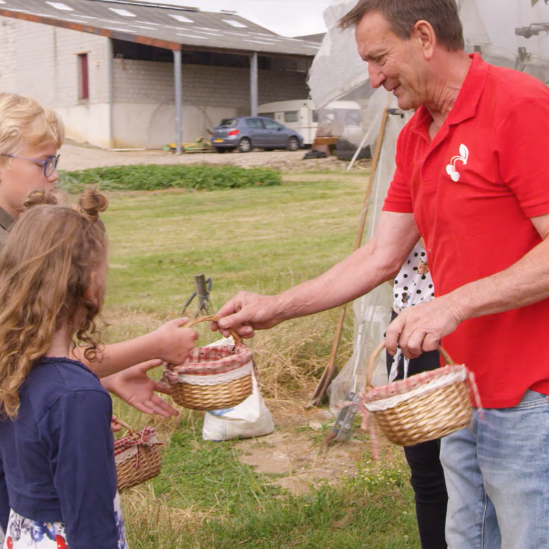 Man geeft mandje aan 2 kinderen op boerderij