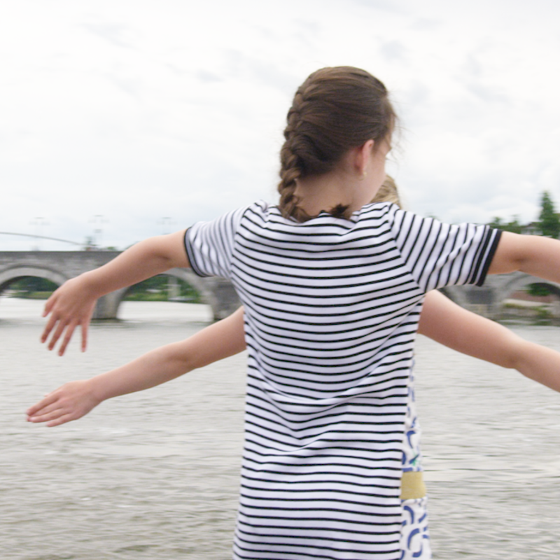 2 meisjes doen Titanic scene op boeg van schip met in de verte de oude brug van Maastricht