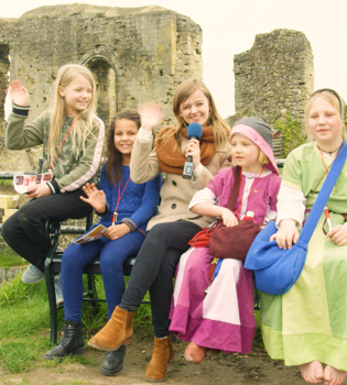 Presentatrice naast verklede kinderen in kasteelruine