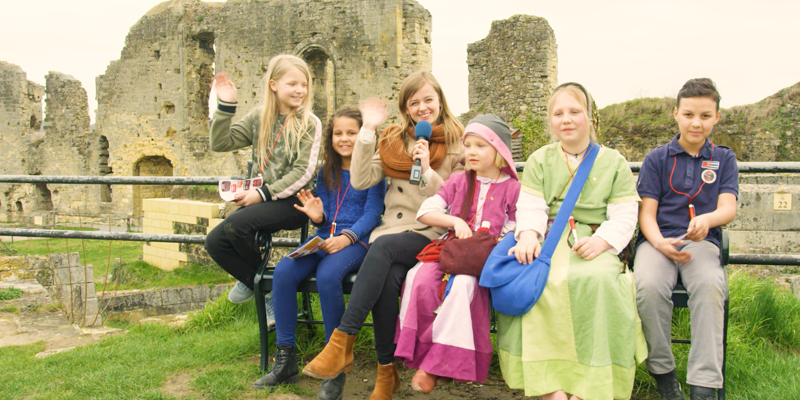 Presentatrice naast verklede kinderen in kasteelruine