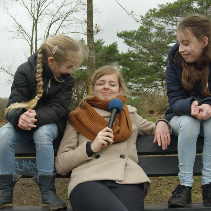 Presentatrice met de jonge meisjes op bankje in Burnssummerheide