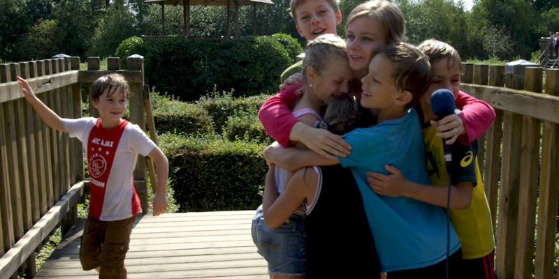 Kinderen knuffelen presentatrice op brug in labyrint