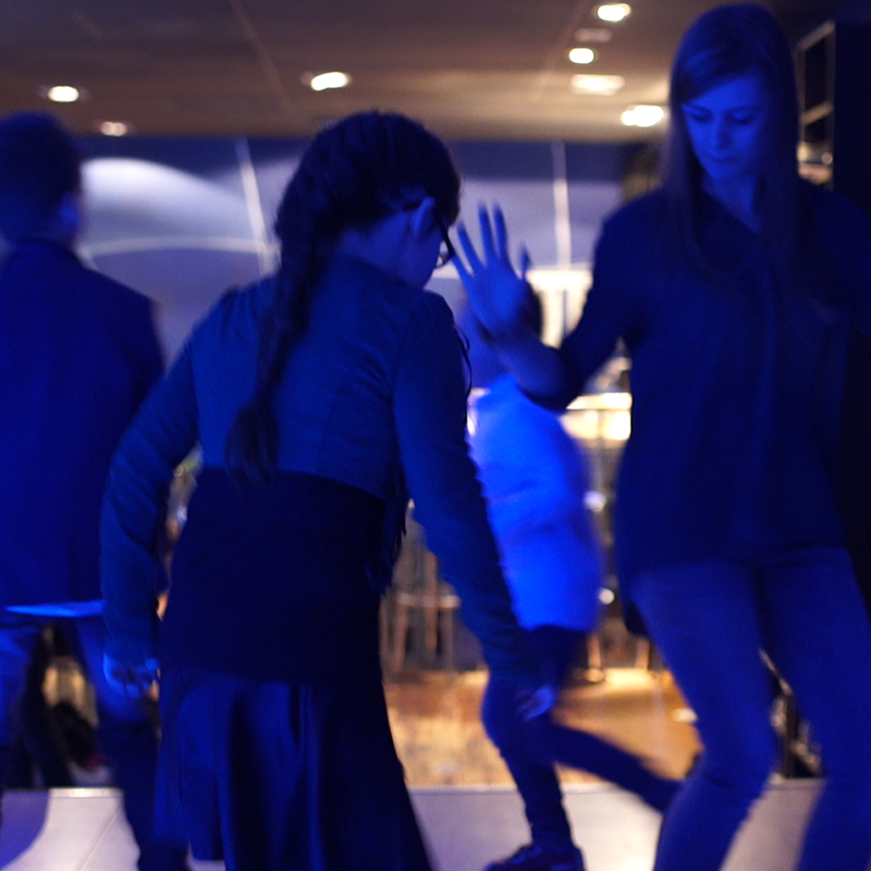 Jonge vrouw en kinderen dansen in blauw licht