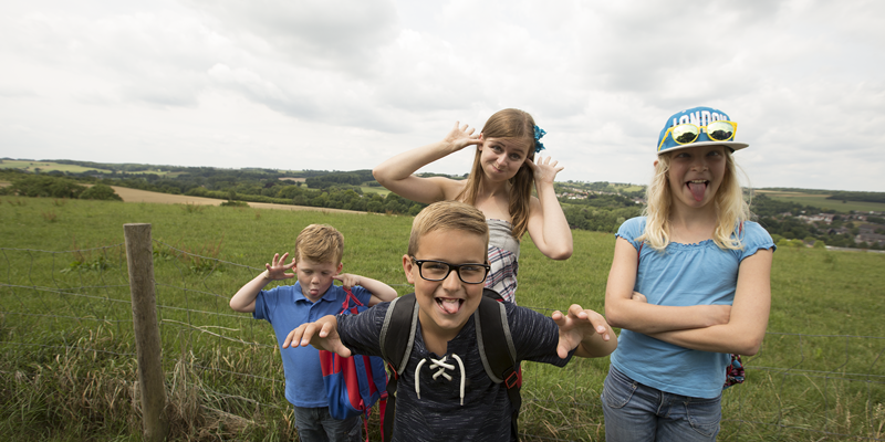 Jonge vrouw en 3 kinderen trekken gekke bekken in weiland