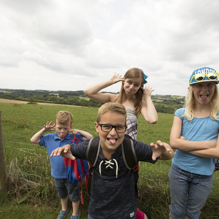 Jonge vrouw en 3 kinderen trekken gekke bekken in weiland