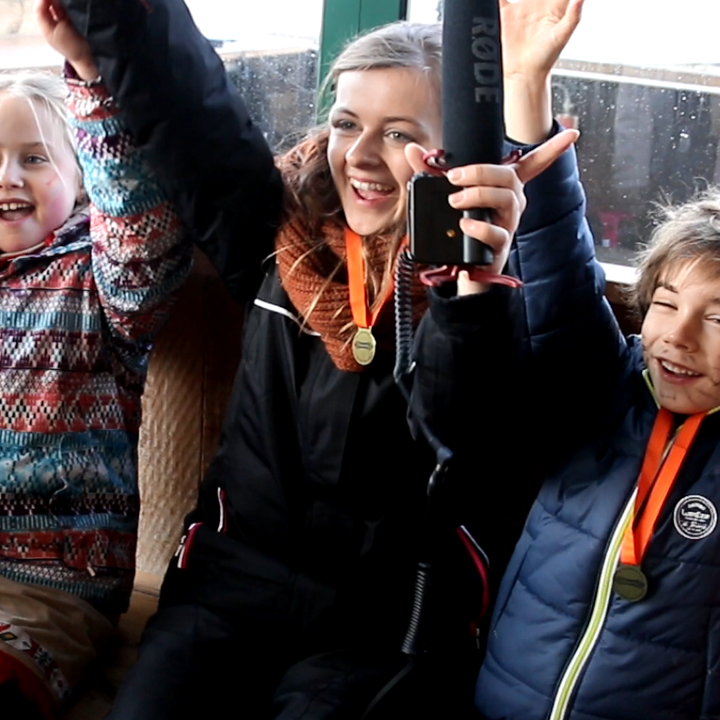 Jonge vrouw en kinderen met medaille om de nek met de handen in de lucht