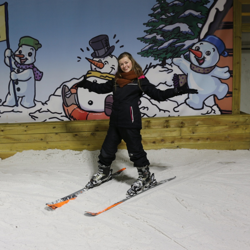 Jonge vrouw op ski's bovenaan de piste bij Snowworld