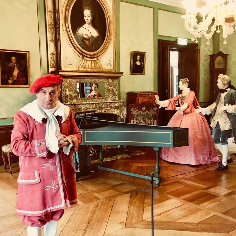 Sleutelbewaarder Kasteel Hoensbroek in kamer met piano en twee mannequins