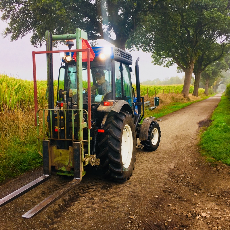 Een jongen rijdt met een mini tractor over een onverharde weg