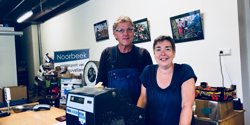 De medewerkers van de fruitgaard poseren lachend achter hun kassa