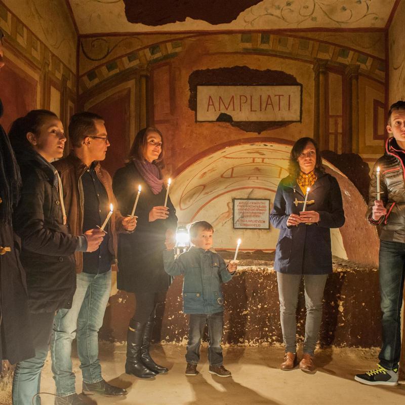 Personen met kaarsjes tijdens een rondleiding door de Romeinse Katakomben in Valkenburg