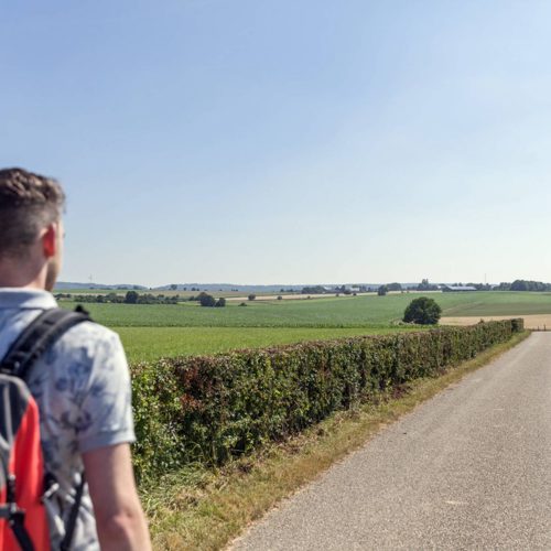 Wandelaar met rugzak over een geasfalteerd pad bij Simpelveld