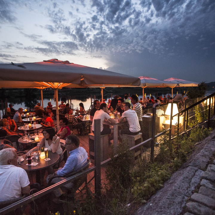 Een druk terras in de avond bij eetcafe Bat Eijsden aan de Maas