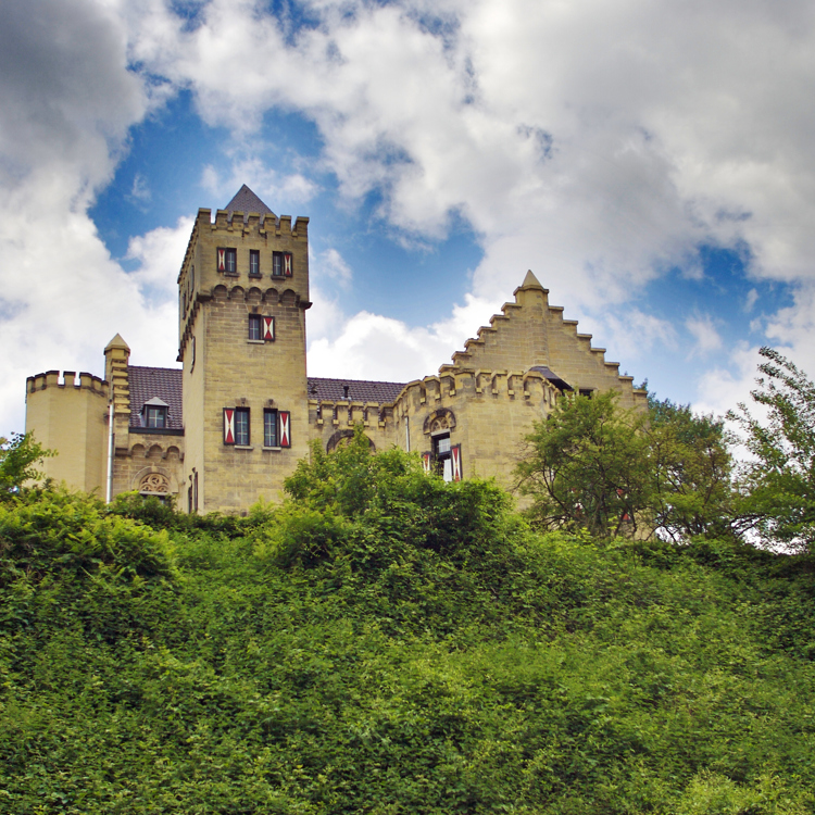 Onderaanzicht richting een helling met veel groen en bovenop een oud kasteel. 