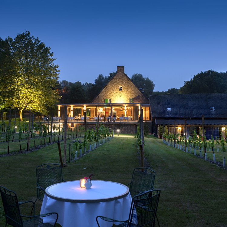 Avondsetting van een tafeltje in een wijngaard bij het sfeervol verlichte hotel. 